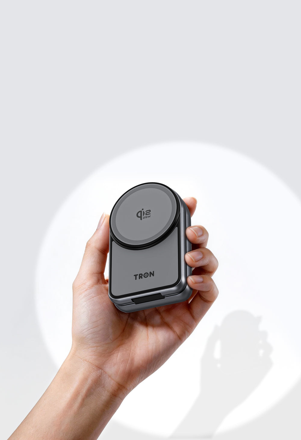 TRON Qi2 charging station folded flat and held in one hand to show its size