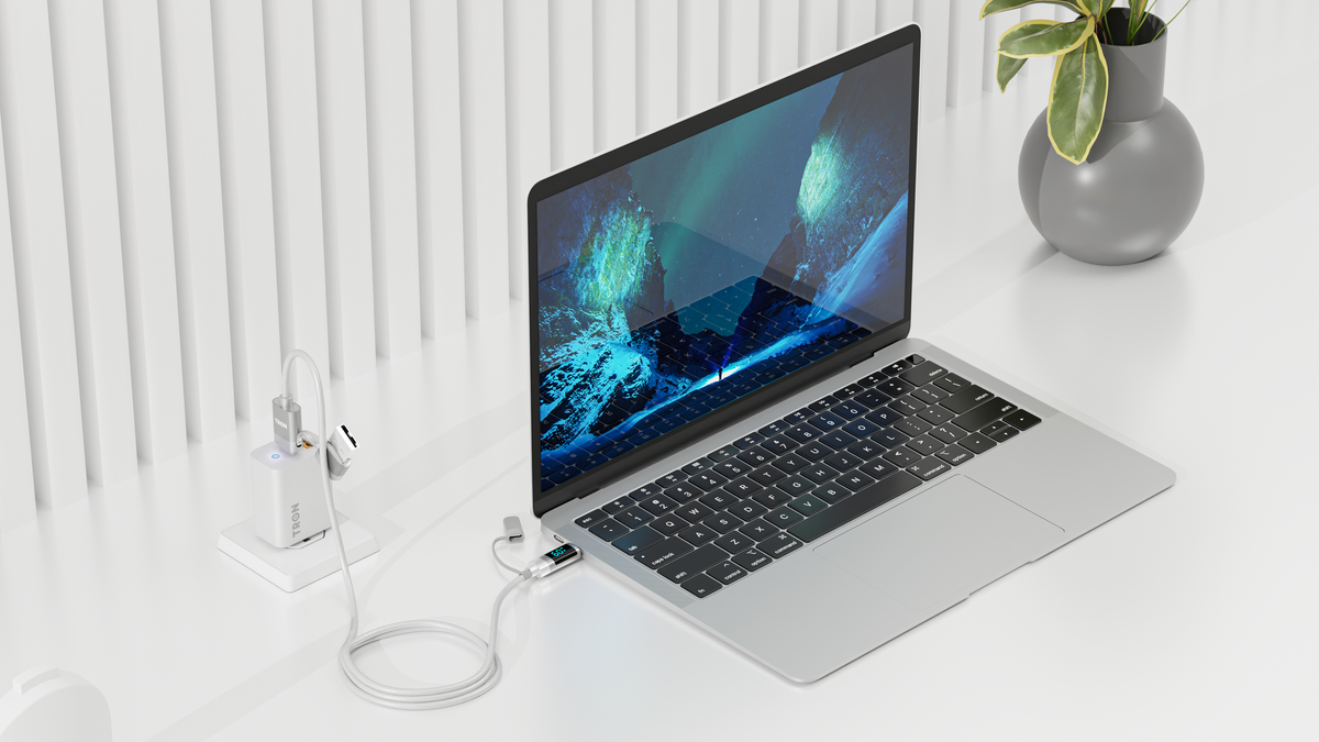 Tron wall charger plugged in beside a laptop